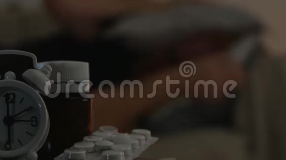 病人卧床休息桌上有药片和闹钟视频的预览图