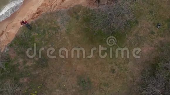 空中拍摄的站在海边粘土悬崖边上的年轻女子勇敢无畏的女孩爱视频的预览图