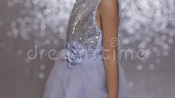 小女孩穿着银色的裙子在银色的背景上跳舞视频的预览图
