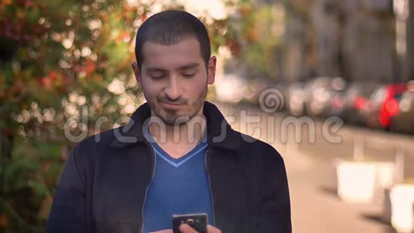 一名白人男子在秋日街头观看智能手机从愤怒到满足的情绪变化视频的预览图