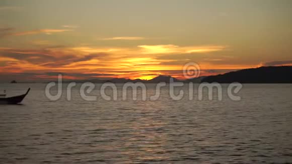 日落时分长尾小船漂浮在平静的水面上视频的预览图