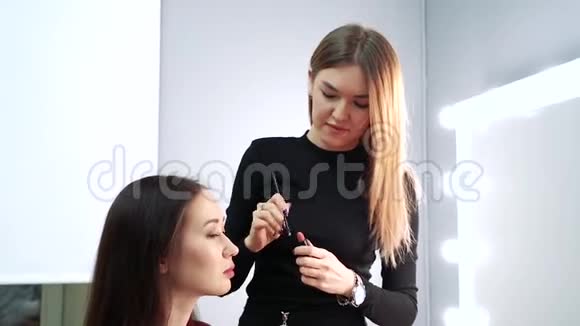 化妆师将唇膏涂抹在美容院模型的嘴唇上视频的预览图