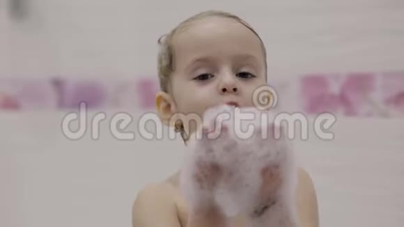 漂亮的三岁女孩洗澡用沐浴泡沫弄湿头发可爱的金发孩子手里拿着泡沫然后吹视频的预览图
