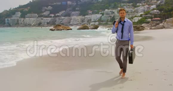 高加索商人带着公文包在海滩散步的正面景色视频的预览图