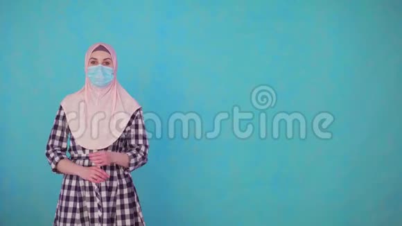 年轻美丽的穆斯林女性戴着医用面具微笑着摘下面具看着镜头视频的预览图