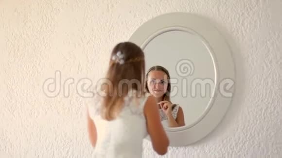 年轻漂亮的女人穿着白色裙子站在镜子前视频的预览图