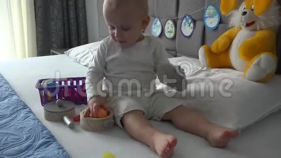 可爱的男孩坐在床上玩厨房玩具快乐的孩子在家玩得开心视频的预览图