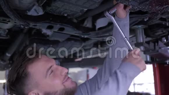 英俊的机械师男汽车车库扳手在汽车底部工作视频的预览图