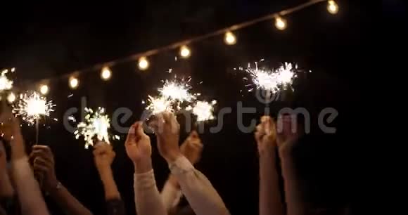 手在黑暗中挥舞着火花在花环的背景下新年假日圣诞节生日聚会开朗的视频的预览图