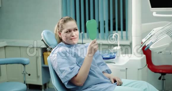 成熟的女性病人在做了一个手术后躺在医疗椅上看着她的脸视频的预览图