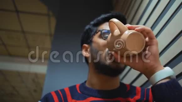 特写镜头下面是一个喝咖啡看智能手机的印度男人视频的预览图