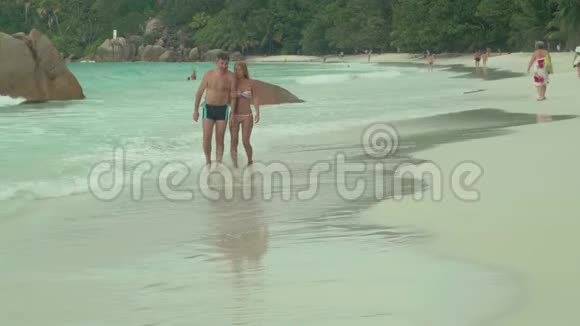 塞舌尔普拉斯林岛在岛上的海滩上休息的美丽幸福的恋爱情侣条纹美女视频的预览图
