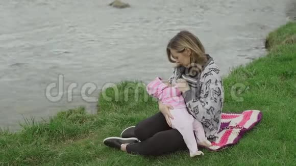 年轻的母亲在户外给她的女婴喂奶视频的预览图