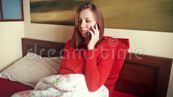 一个年轻的女人在用手机说话在床上的女孩视频的预览图