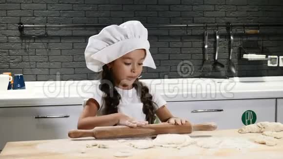 可爱的学龄前小女孩在家厨房里当厨师儿童厨师概念美丽的黑发女孩视频的预览图