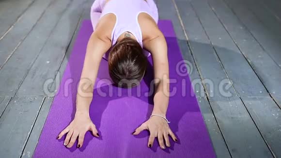 年轻有魅力的女人练习瑜伽坐在锻炼巴拉萨纳姿势视频的预览图