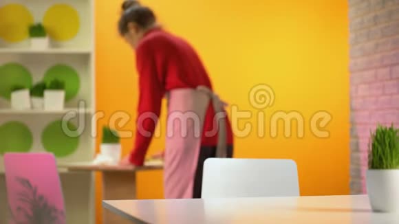 美丽的女性咬美味的芝士汉堡女服务员清洁桌子背景视频的预览图