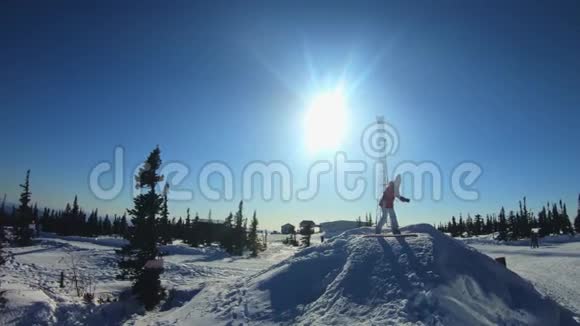 快乐美丽的年轻女孩滑雪板在滑雪板上做一个把戏在雪地里蹦蹦跳跳视频的预览图