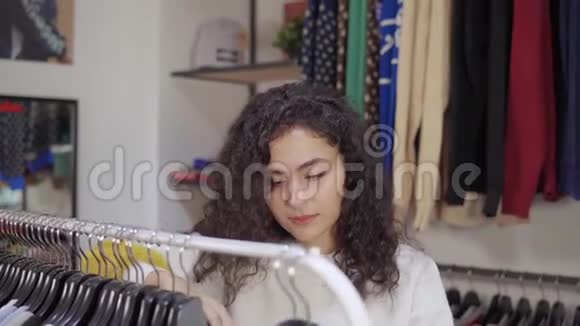 一个女人在商场的服装店买衣服从衣架上拿衣架视频的预览图