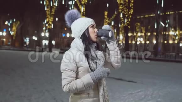穿着温暖衣服的女孩在冬天的广场上喝杯咖啡视频的预览图