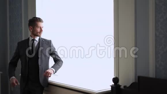 男人时尚和风格室内窗户旁英俊的年轻新郎的肖像视频的预览图