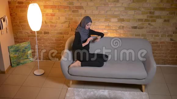 特写侧景照片成年穆斯林女性在头巾上网时悠闲地坐在网上视频的预览图
