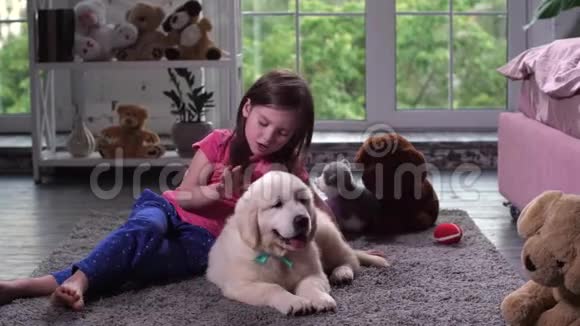 可爱的女孩和坐在地板上的小狗玩耍视频的预览图