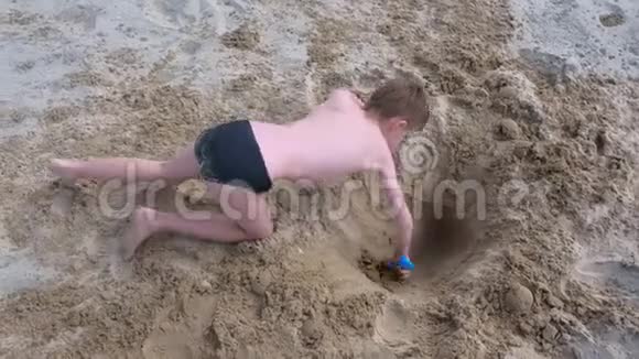 暑假小男孩在沙滩上玩挖铲深洞视频的预览图