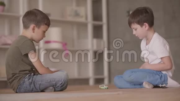 两个弟弟坐在地板上玩玩具汽车坐在地板上在家里小兄弟花时间视频的预览图