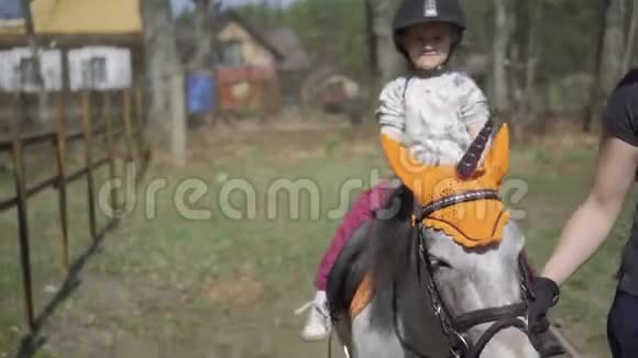 快乐可爱的女孩一边挥动手一边骑独角兽小马万向节运动视频的预览图