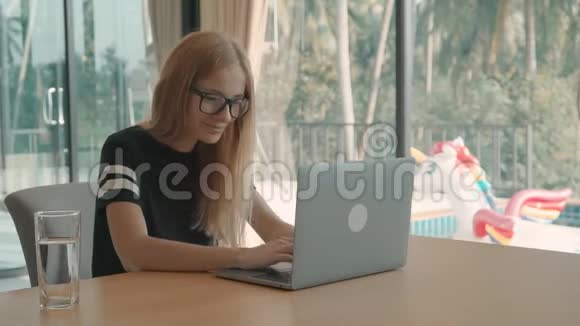 白天金发女人坐在家里的笔记本电脑上自由职业概念视频的预览图