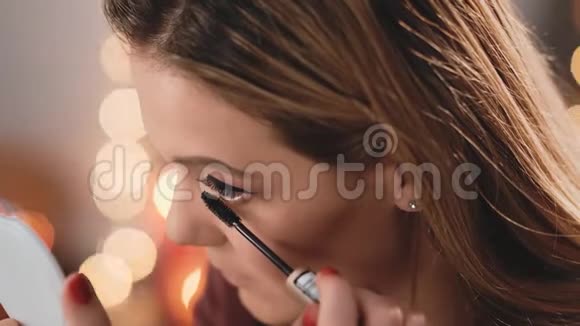 白人模特金发用睫毛膏涂睫毛化妆生意的女人圣诞节背景下的慢动作视频的预览图