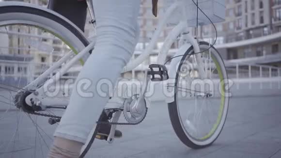 穿着浅蓝色牛仔裤的年轻人在城市里骑着自行车英俊城市居民的休闲积极主动视频的预览图