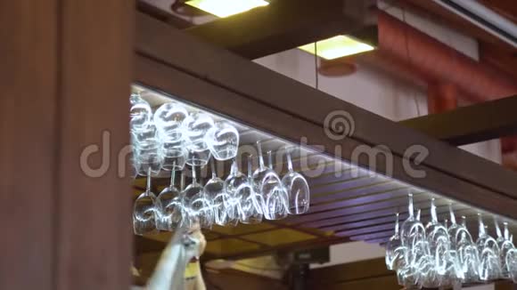 酒保把一个干净的酒杯挂在酒吧上方的一个特殊的支架上酒吧里的木头内部视频的预览图