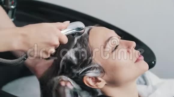 美发师用洗发水近距离给美容院的女人洗头视频的预览图