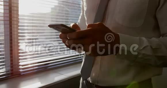 中段白种人年轻男性高管使用手机靠近窗口在现代办公室4k视频的预览图