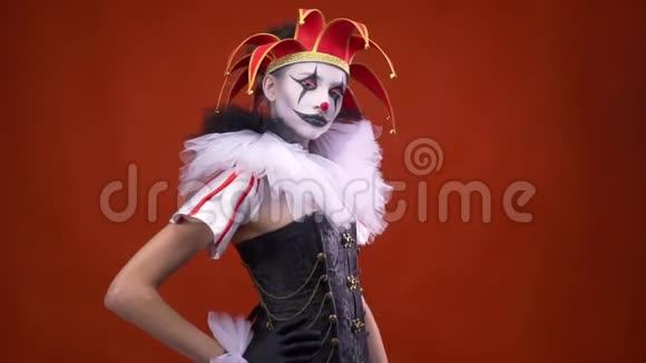 一个化妆着装戴着帽子的女小丑正在画室里摆姿势吹着一个吻视频的预览图