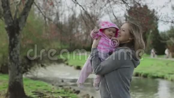 妈妈和她的小宝贝女儿一起玩春天公园阳光明媚的一天公园里快乐的妈妈和孩子视频的预览图