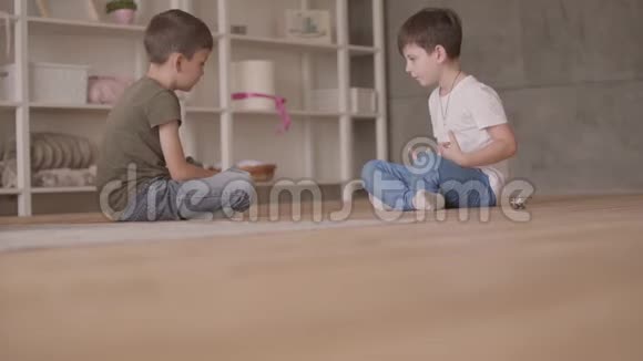 两个可爱的兄弟坐在地板上玩玩具车坐在地板上在家里小兄弟花时间视频的预览图