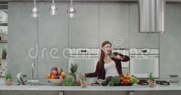 年轻漂亮的女士花时间在厨房里跳舞早上做食物时动作滑稽视频的预览图