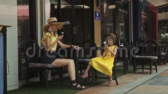 母亲和女儿在夏日的街头咖啡馆吃冰淇淋视频的预览图