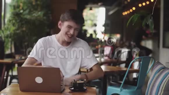 年轻的欧洲男人在咖啡馆里笑着自由职业者和博客作家在室内和现代的交流中聊天视频的预览图