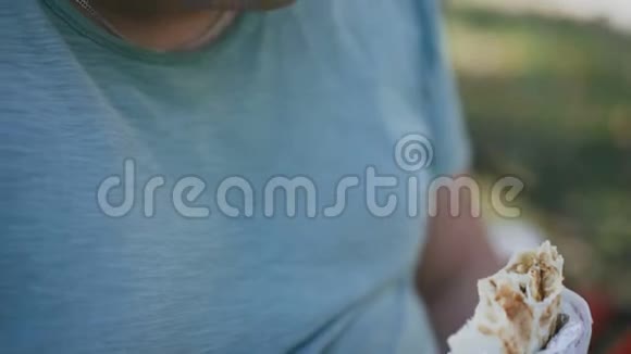 一个在户外长凳上吃有害快餐和喝咖啡的胖子视频的预览图