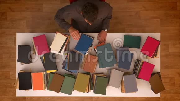 停止移动顶部镜头的人移动他的手高于消失的书籍在桌子上下载他们的笔记本电脑视频的预览图