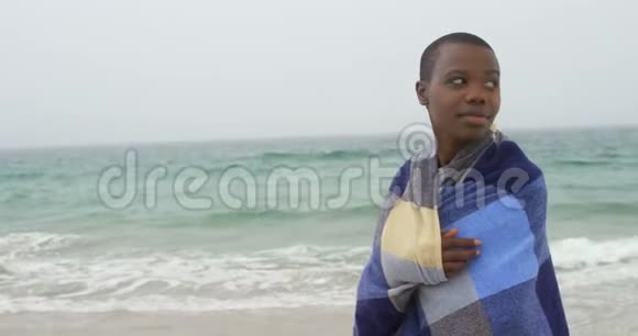 海滩上裹着毯子的非洲裔美国妇女的正面景色视频的预览图