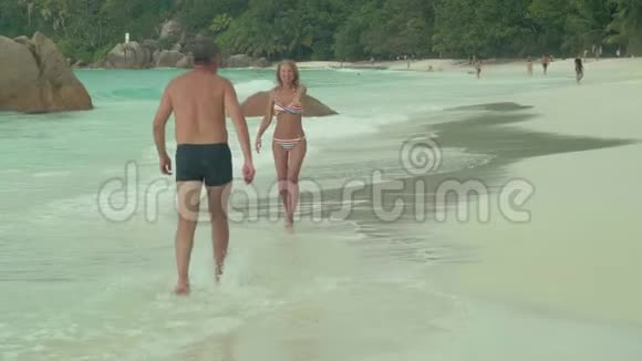 塞舌尔普拉斯林岛美丽幸福的夫妇在岛上的海滩上休息穿条纹泳装的美女视频的预览图