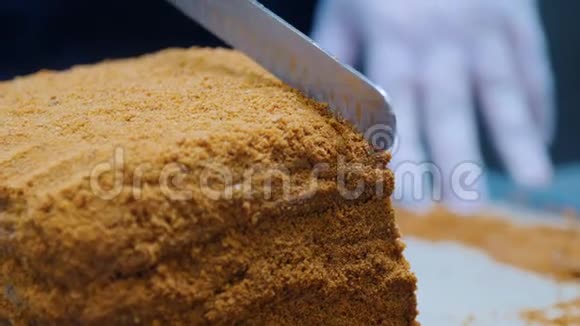 一个男人用刀切自制的蜂蜜蛋糕然后把它放在盘子里视频的预览图
