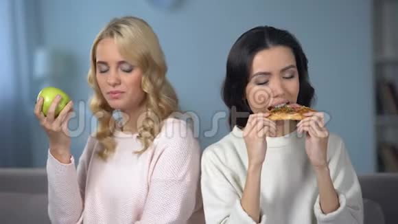 女士吃披萨女朋友吃绿苹果健康饮食选择视频的预览图