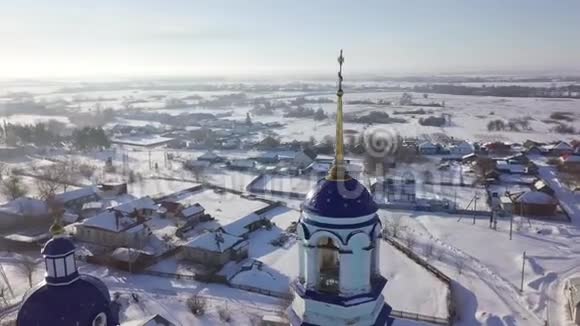 在晴朗的冬天在小村庄附近的俄罗斯东正教教堂的蓝色圆顶和金色十字架的近景视频的预览图