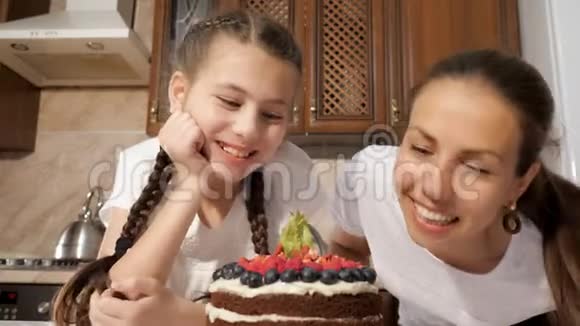 快乐的妈妈和女儿正在嗅着用浆果做的巧克力蛋糕视频的预览图